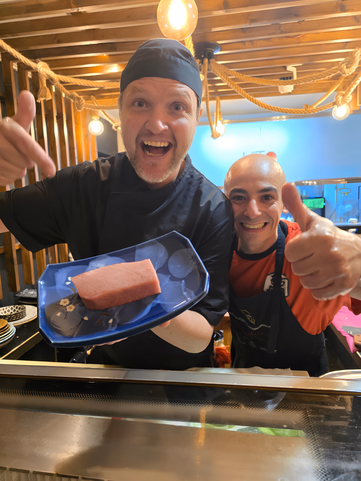 Oliver Schultz sosteniendo un bloque entero de atún rojo Balfegó en la barra de Hito, junto a un compañero levantando el pulgar