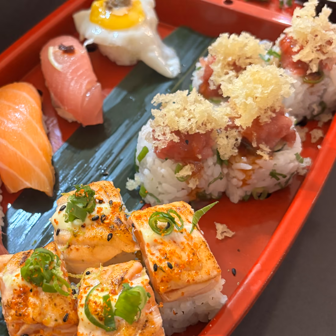 Uramaki Netto Roll topped with flamed tuna and avocado on a red lacquered boat at Hito