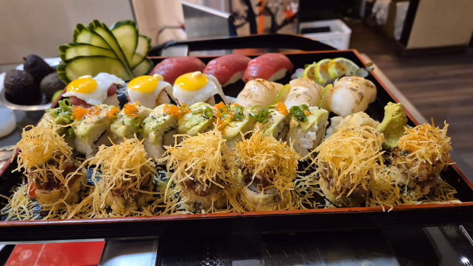 A sushi platter at Hito - tuna nigiri, avocado uramaki and crisp-topped rolls on a lacquered tray