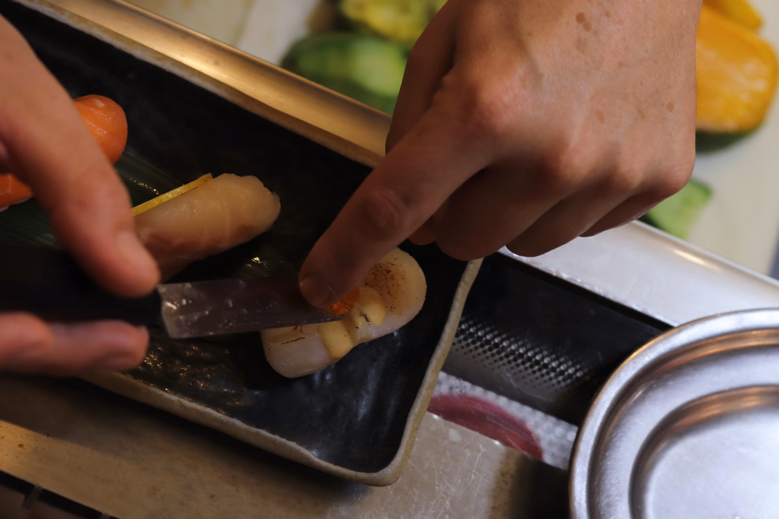 Las manos del chef cortando pescado fresco en la cocina de Hito