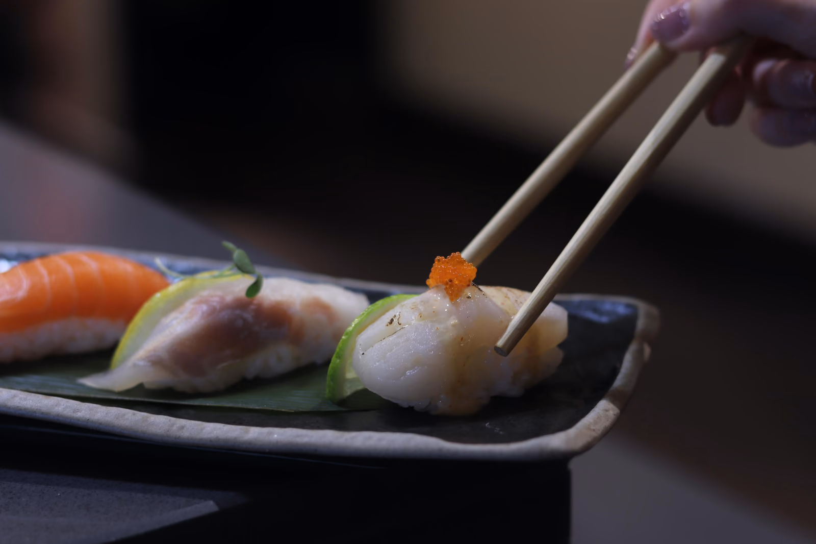 Un chef rematando un nigiri con hueva usando palillos en Hito