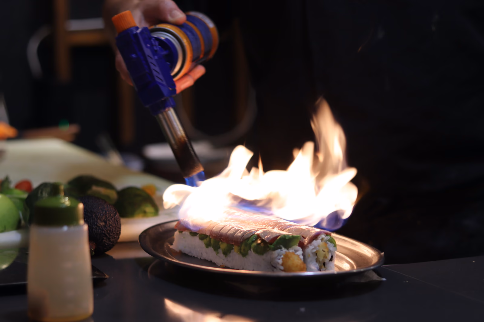 Un chef flameando un nigiri con soplete en la barra de sushi de Hito
