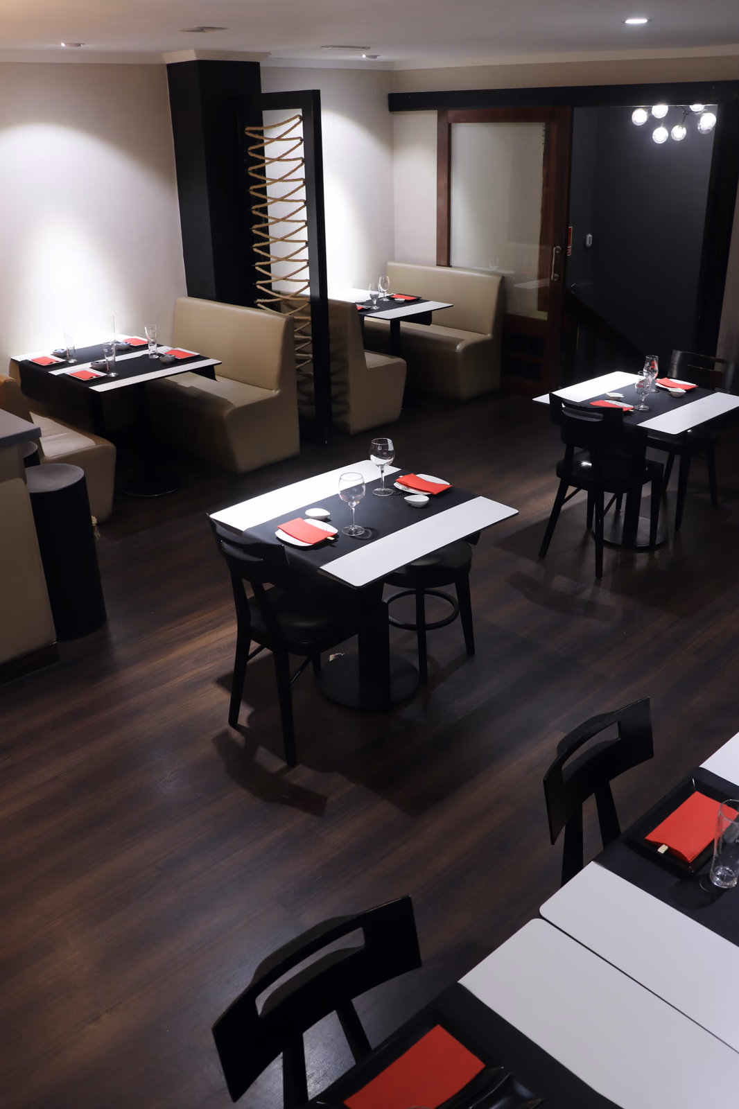 Comedor de Hito con mesas de madera oscura, bancos beige y caminos de mesa rojos