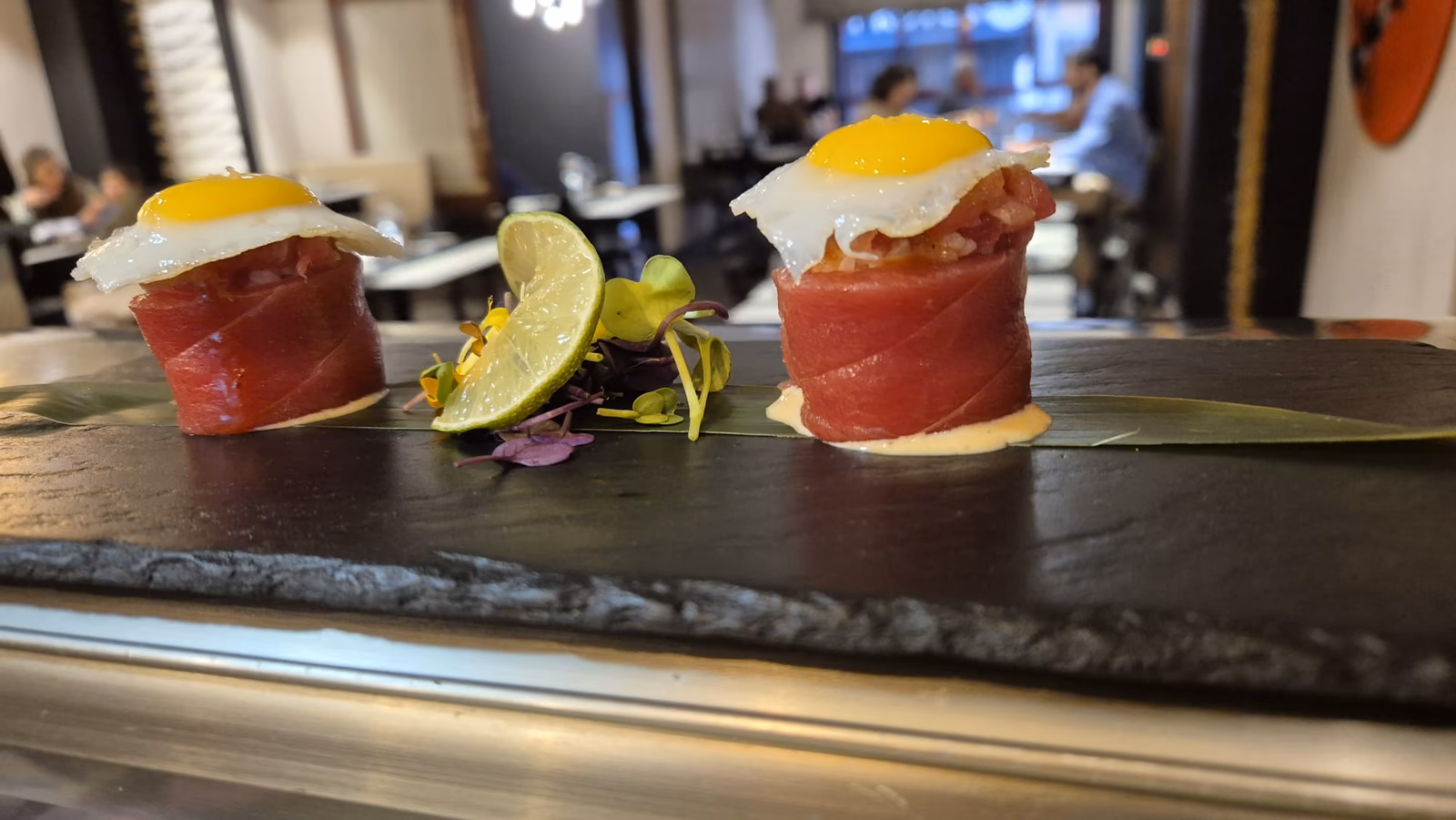 Nigiri de atún rojo coronado con huevo de codorniz sobre pizarra en Hito