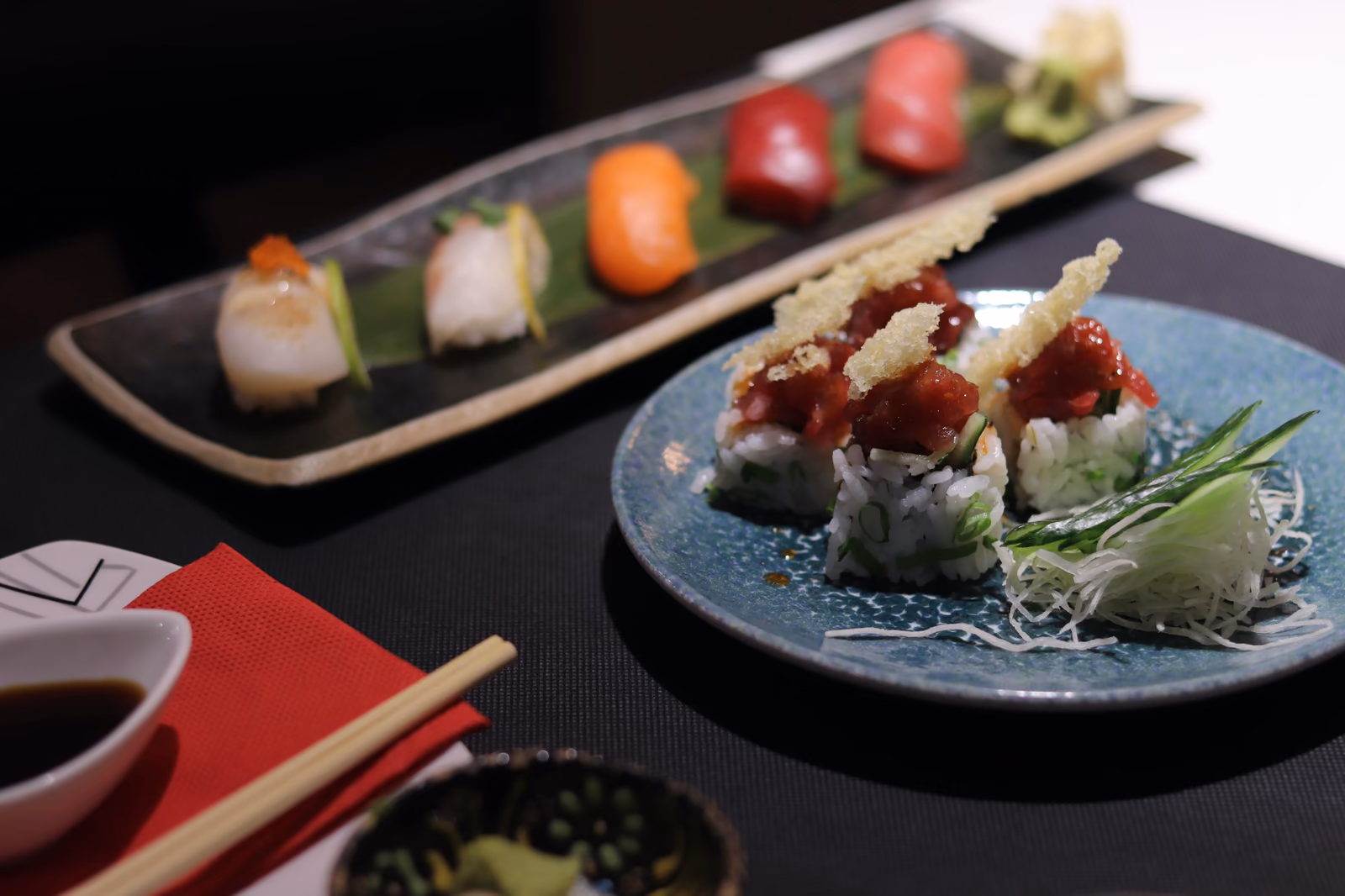Una selección de nigiri y uramaki con salsa en un plato azul en Hito