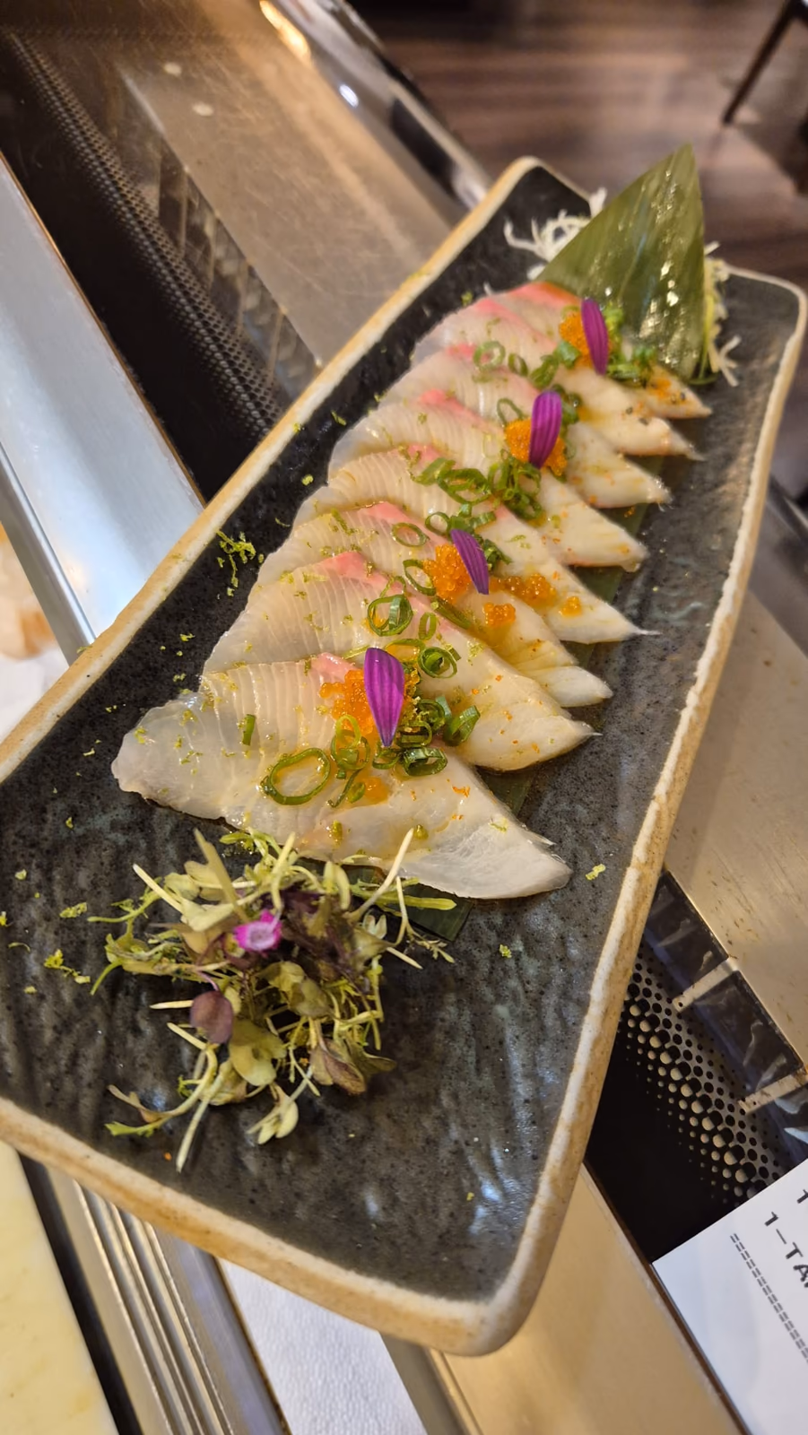 Sashimi de pescado blanco con hueva, cebolleta y flores comestibles en Hito