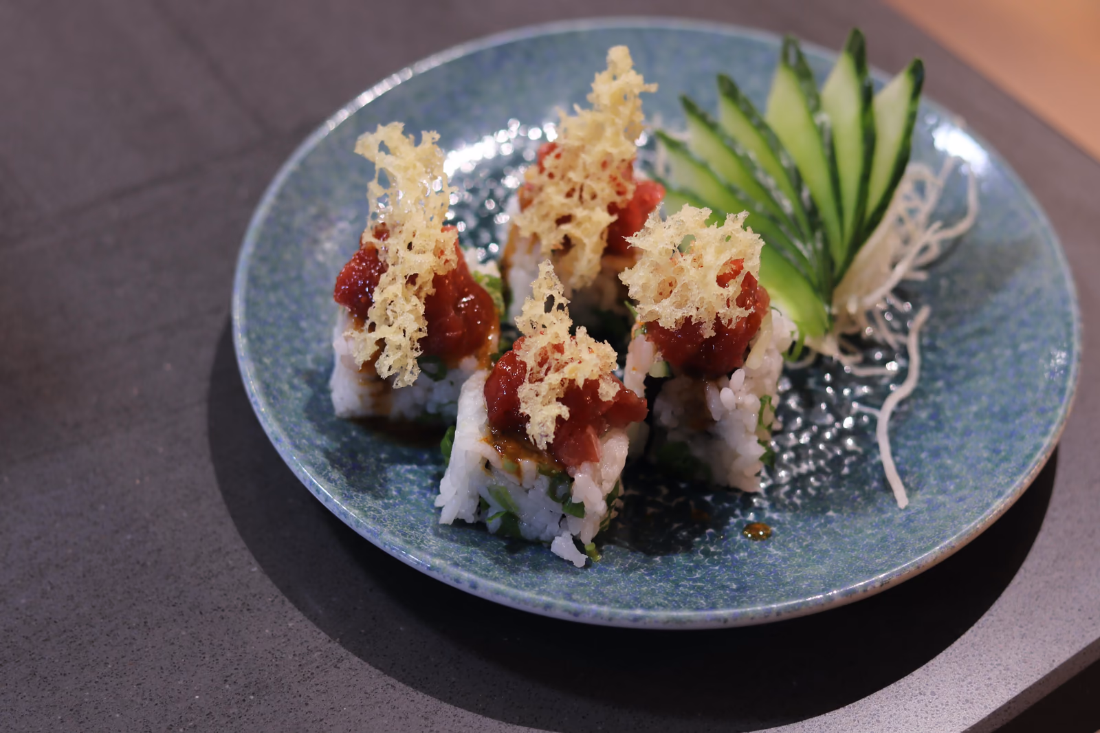 Uramaki con tartar de atún y tempura crujiente en un plato azul en Hito