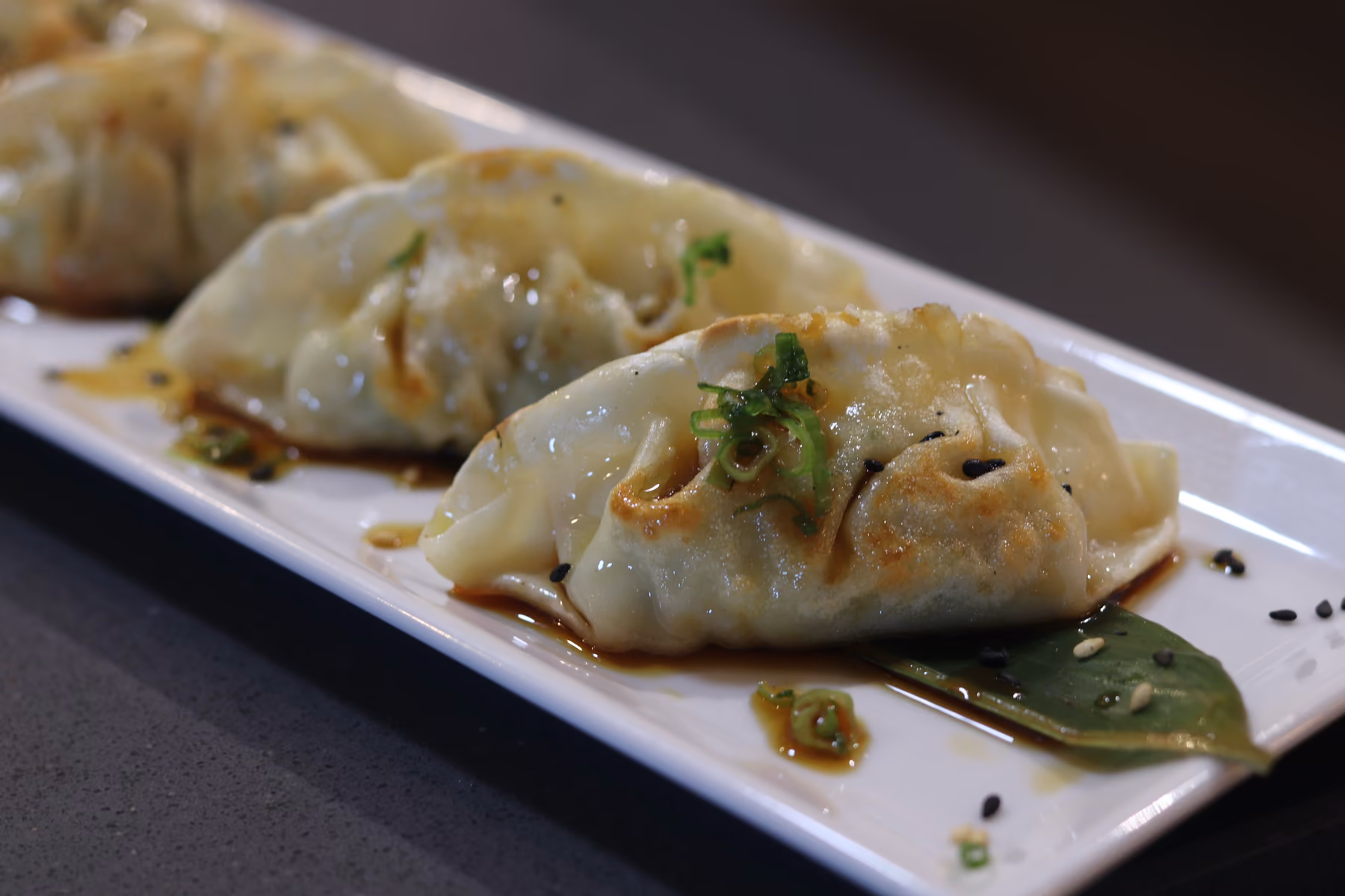 Grilled gyoza glazed and finished with spring onion and sesame at Hito