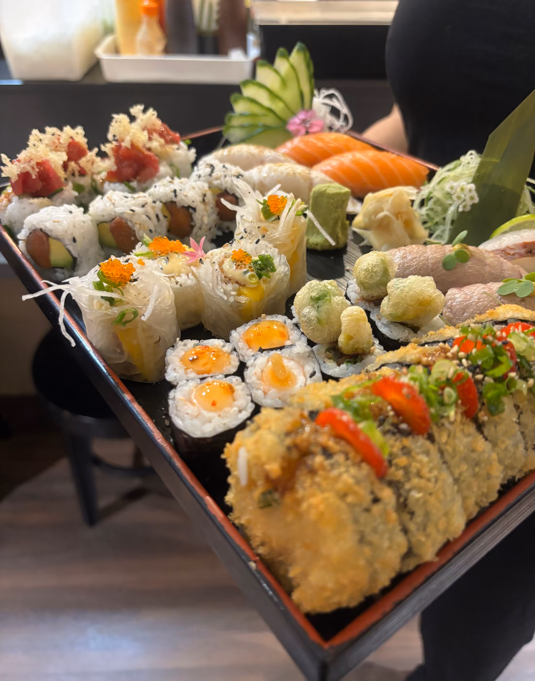 A large sharing tray of maki, uramaki and nigiri carried to a table at Hito