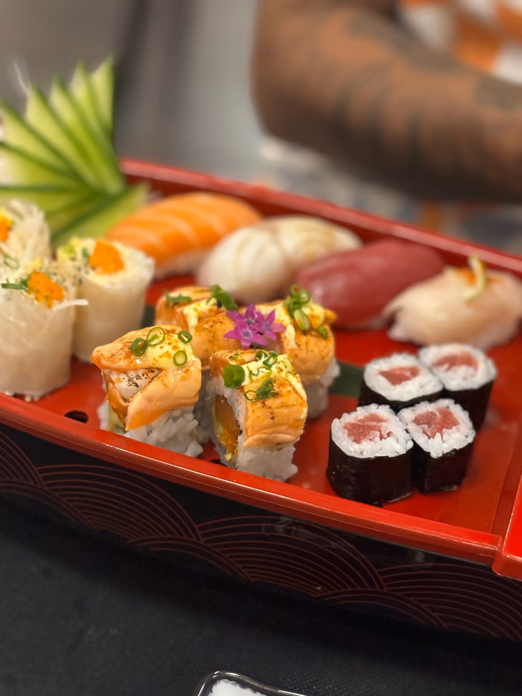 Un barco de sushi de laca roja en Hito con nigiri, hosomaki y rollos con topping crujiente