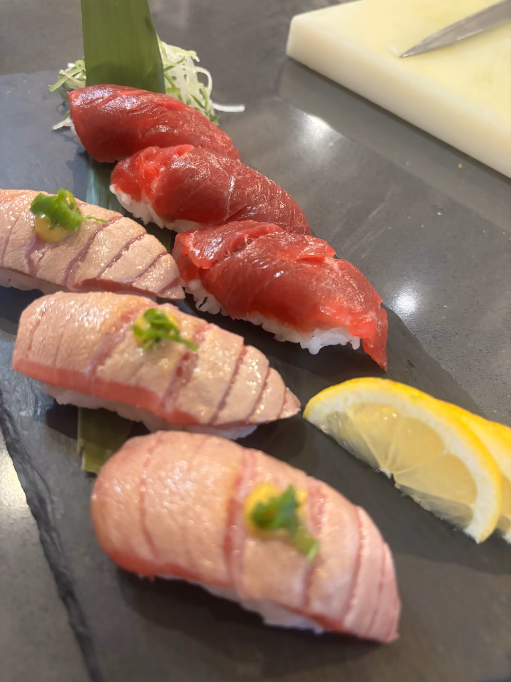 Una fila de nigiri cortados al momento en la barra de Hito