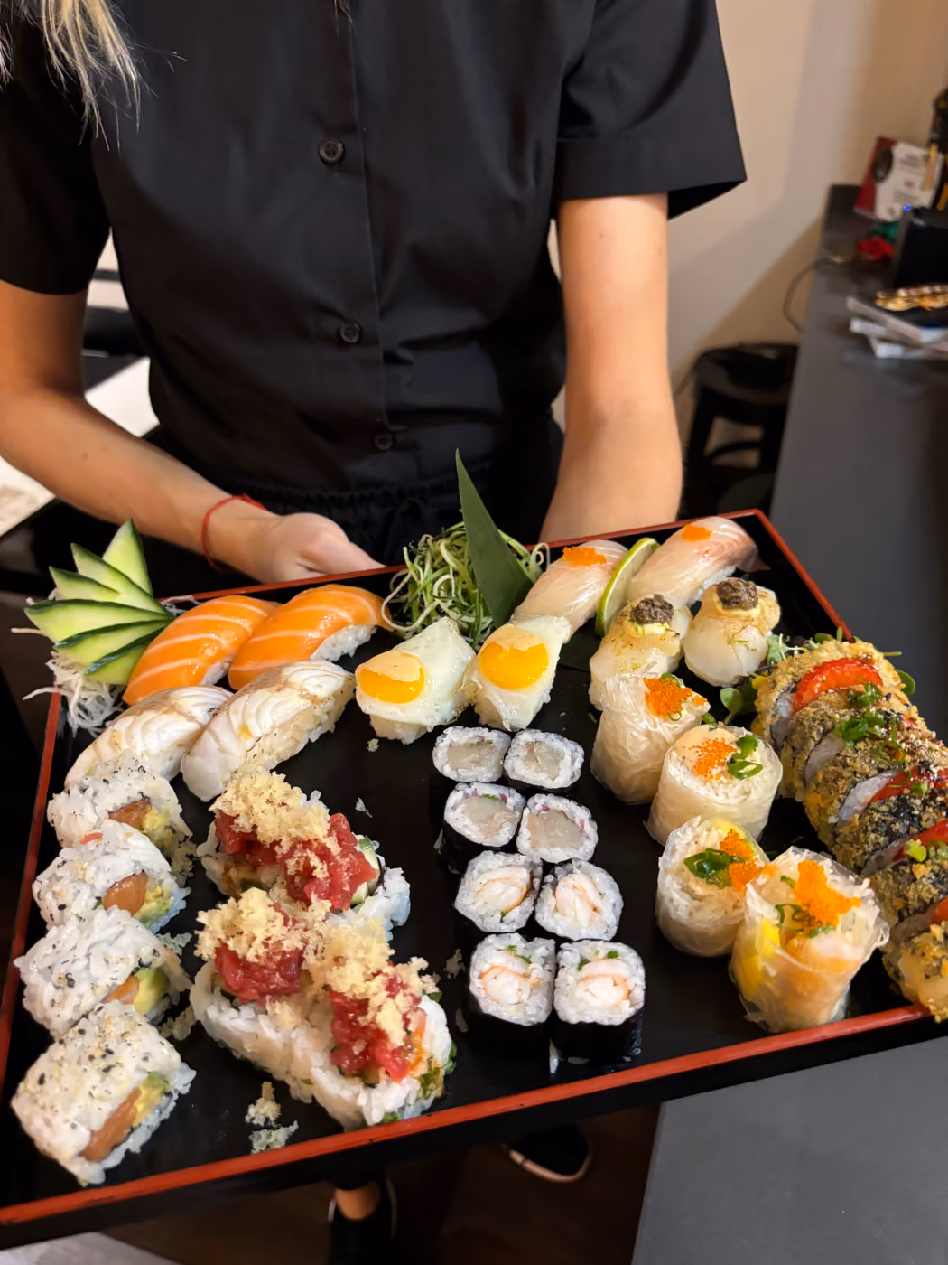 Un camarero de Hito llevando a la mesa una gran bandeja de nigiri, uramaki y maki
