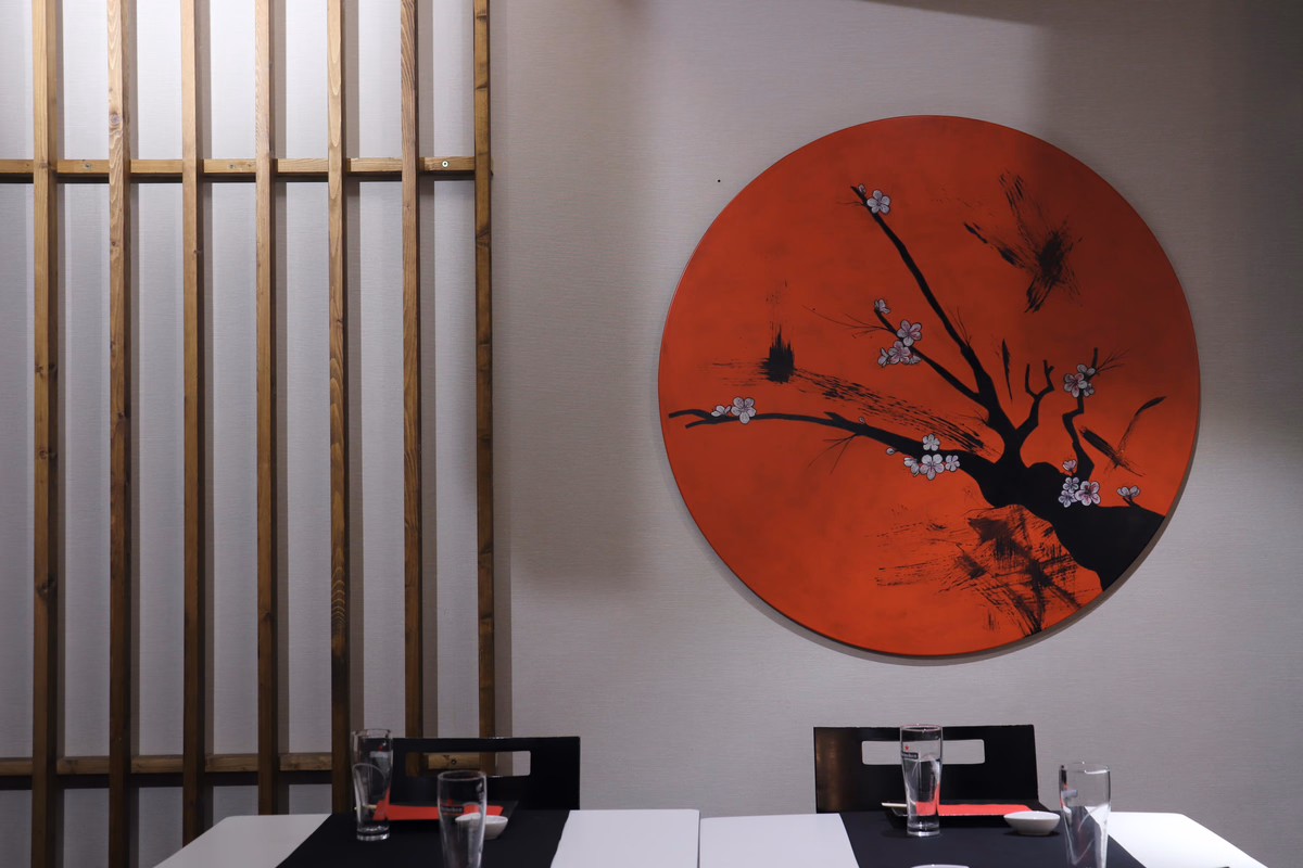 Cherry-blossom painting on a red disc beside a wooden slat screen in Hito's dining room, Las Palmas