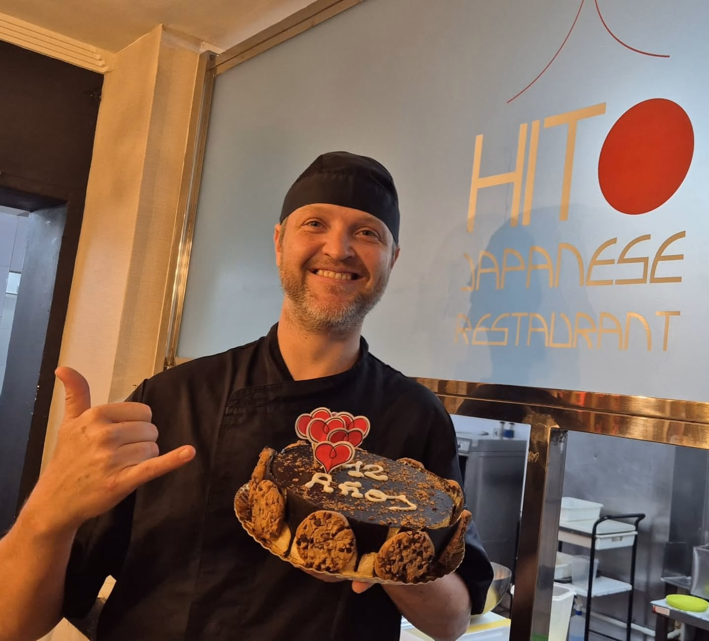 Oliver Schultz, copropietario de Hito, sosteniendo una tarta de celebración dentro del restaurante